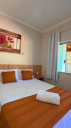 a bedroom with two beds and a window at Pousada Ipê do Lago in Capitólio