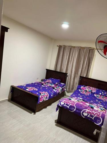 two beds in a room with purple sheets at لاسرينا عيون موسي in Az Zaytīyah