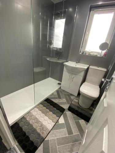 a bathroom with a toilet and a glass shower at Pure Home Oakley Central TBA in Dunfermline