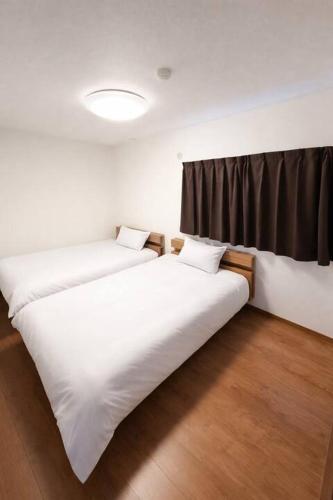 two beds in a room with a window at Arch Garden in Ishihara
