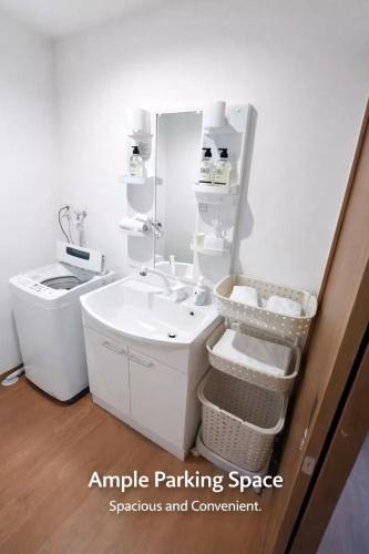 a white bathroom with a sink and a mirror at Arch Garden in Ishihara