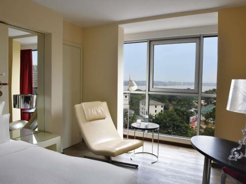a bedroom with a bed and a chair and a window at Pullman Kinshasa Grand Hotel in Kinshasa