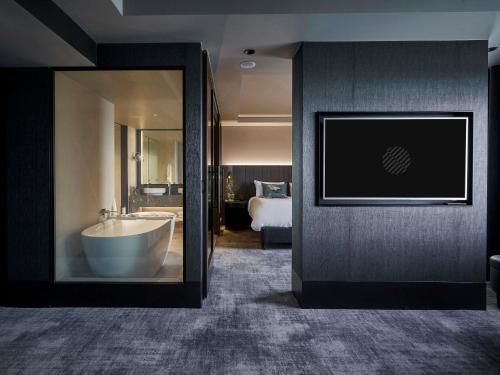 a bathroom with a tub and a bedroom with a bed at Pullman East Melbourne in Melbourne