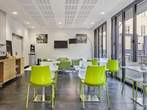 a cafeteria with white tables and green chairs at Aparthotel Adagio Access Paris Bastille in Paris