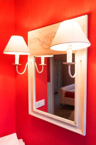 two lights on a red wall with a mirror at Jungbrunnen Orges in Orges
