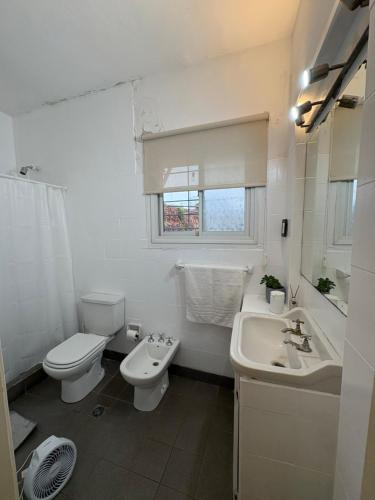 a white bathroom with a toilet and a sink at Lo de Mingo in San Pedro