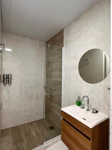 a bathroom with a shower and a sink and a mirror at Vela Villa Apart N3 in Villa Ángela