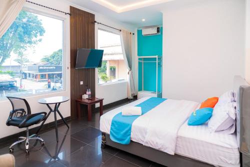 a bedroom with a bed and a desk and a tv at SANS Hotel Bobo Home Jambi in Jambi