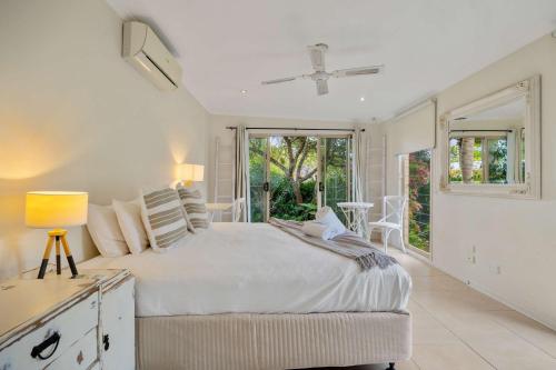 a white bedroom with a bed and a window at Noosa Sunrise - Pet-friendly with Pool in Sunrise Beach