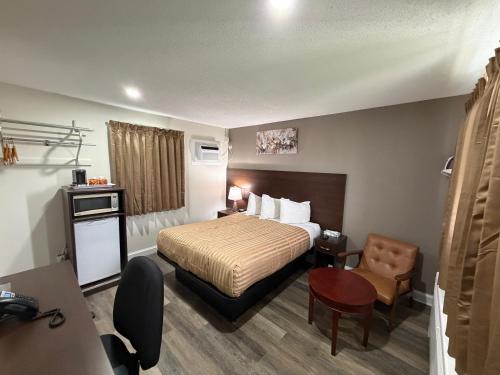 a hotel room with a bed and a chair at Perth Plaza Inn & Suites in Perth