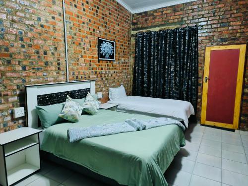two beds in a room with a brick wall at Acasa do Delco Accommodatiion in Welkom