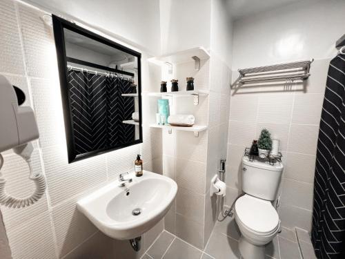 a white bathroom with a toilet and a sink at Zara at Mesavirre Bacolod in Bacolod