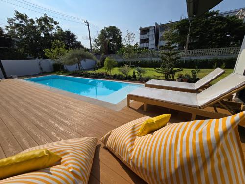 a swimming pool with two lounge chairs and a couch at DRIZZLE pool and pillows in Phra Khanong