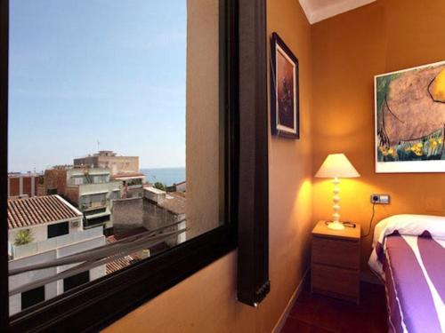 a bedroom with a window with a view of a city at Beach Apartment Santissima in Canet de Mar
