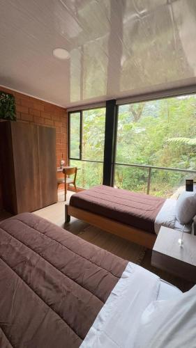 a bedroom with two beds and a large window at SAMAY FOREST- MASHPI AMAGUSa in Mashpi