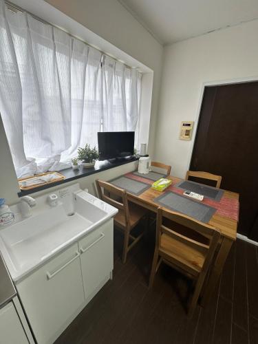 a kitchen with a sink and a table with chairs at Panda Home Umeda 01 in Osaka