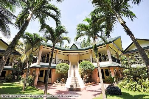 a house with palm trees in front of it at Paradise Garden Hotel and Convention Center Boracay Powered by ASTON in Boracay