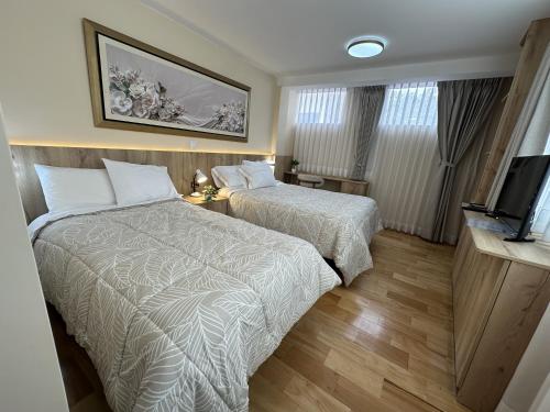 a hotel room with two beds and a television at CASA ETEN Hospedaje Boutique - centro histórico de Cajamarca in Cajamarca
