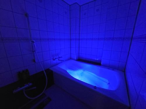 a bathroom with a blue tub in a tiled room at Hotel WIN in Fukaya