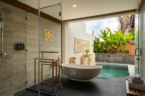 a bathroom with a tub and a swimming pool at Sarva Ubud Villas & Spa in Ubud