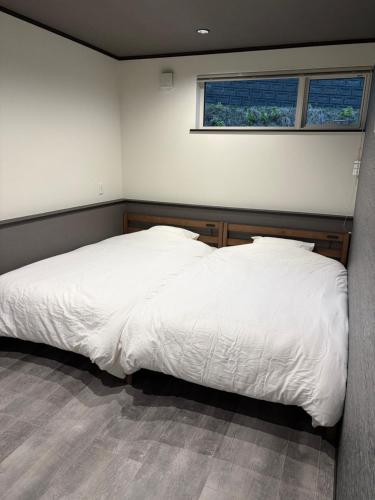 a bedroom with a large white bed with a window at Sugi Nest Rausu-villa- in Rausu