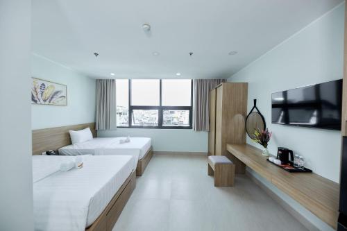 a hotel room with two beds and a television at Cherry Airport Hotel and Apartment 2 in Ho Chi Minh City