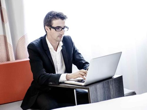 a man sitting at a table with a laptop computer at Novotel Yanbu Albahr in Yanbu