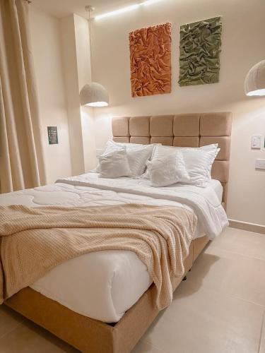 a bedroom with a large bed with two paintings on the wall at CityZen Apartahotel in Florencia