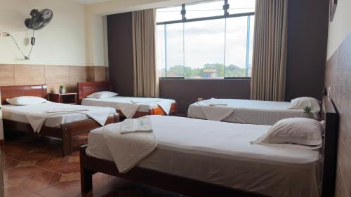 a room with three beds and a window at Hospedaje Maju Del Oriente in Pucallpa