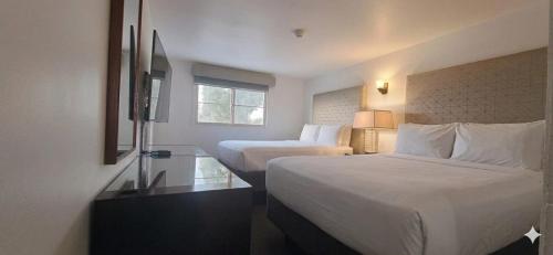 a hotel room with two beds and a window at Hotel Palmas Quintero in Rosarito Beach
