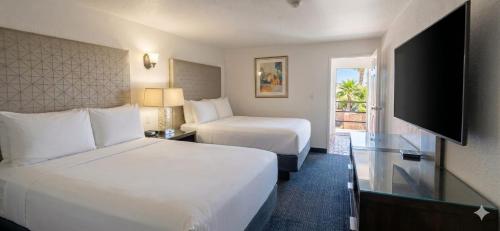 a hotel room with two beds and a television at Hotel Palmas Quintero in Rosarito Beach