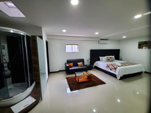 a bedroom with a bed and a couch and a television at Hotel Cafeira in Pereira