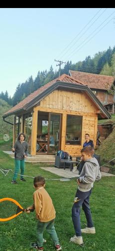 a group of children playing with a kite in front of a house at Planinski Mir in Zaovine