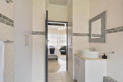 a white bathroom with a sink and a mirror at Elyon Suites in Kempton Park
