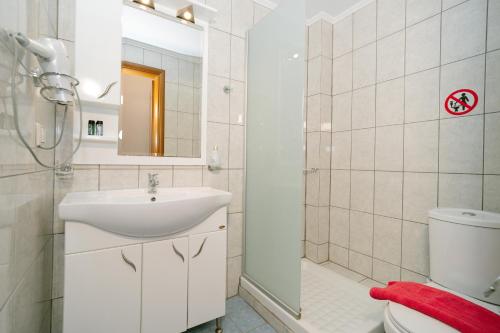 a bathroom with a sink and a toilet and a shower at Hotel Alexandros in Ammoudia