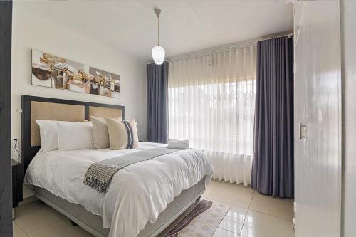 a bedroom with a large bed and a window at Elyon Suites in Kempton Park