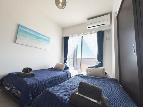 two beds in a room with a window at Maison deLacue in Uruma