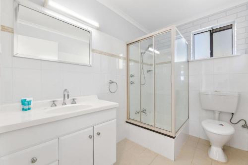 a white bathroom with a sink and a toilet at Forsters Bay Haven in Narooma
