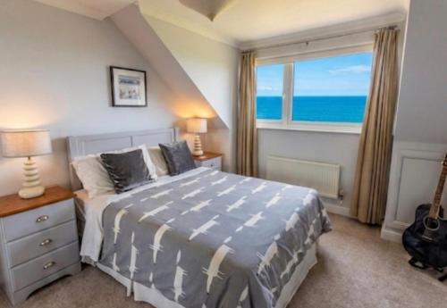 a bedroom with a bed and a window with the ocean at Halekulani Devon Homestay in Torquay