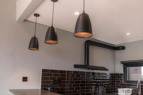 a kitchen with three pendant lights hanging from the ceiling at Iris Apartment in Dalung