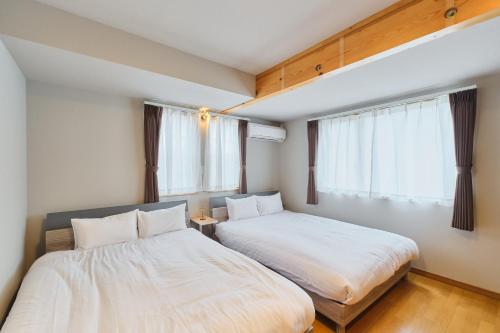 two beds in a small room with windows at 星宿 Sirius in Asahikawa