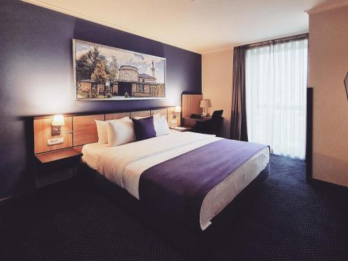 a hotel room with a large bed and a window at Mercure Tetovo in Tetovo
