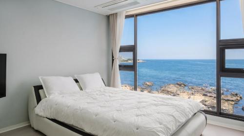 a bedroom with a bed with a view of the ocean at Pohang Pine Wave Pension in Pohang