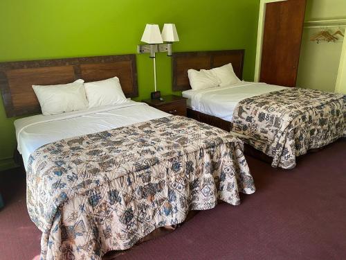 two beds in a hotel room with green walls at Budgetel Inn & Suites in Yuma