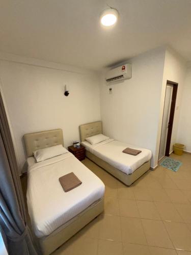 a room with two beds in a hotel room at Amzar Motel Cenang in Pantai Cenang