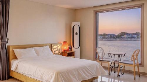 a bedroom with a bed and a view of the water at Daebudo (Yeongheungdo) Dunia Spa Pension in Incheon