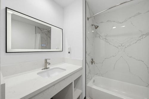 a white bathroom with a sink and a shower at Hyland Inn Van Nuys in Van Nuys