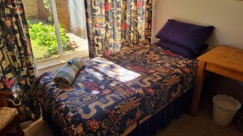 a bedroom with a bed with a blanket and a window at Highway Haven in Stilfontein