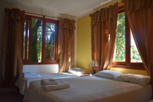 two beds in a bedroom with two windows at Benitez Hostería in Calilegua