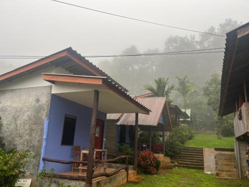 a small blue house with a porch in the fog at โบว์ ปางอุ๋ง in Ban Huai Makhuea Som